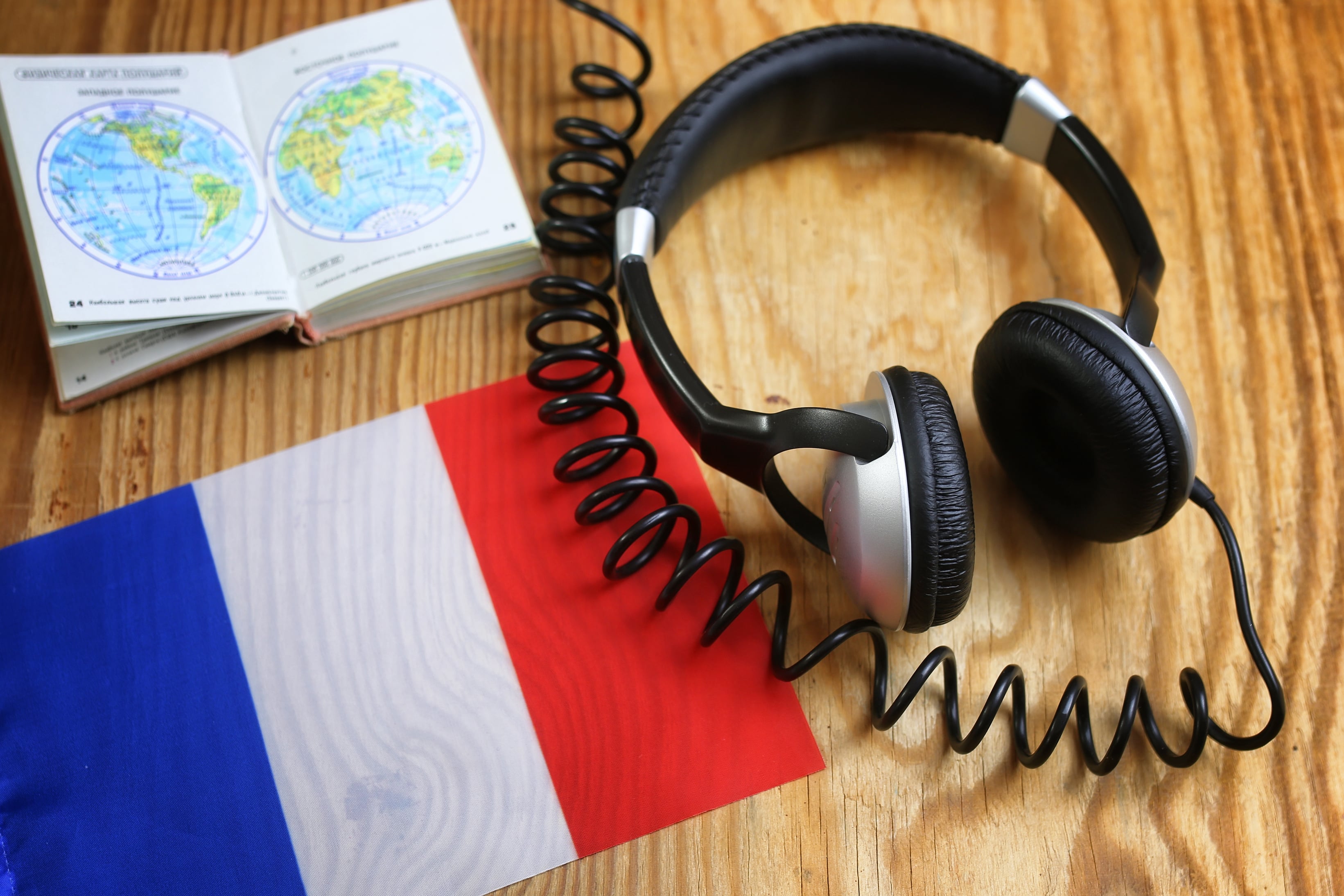 language-course-headphone-flag-wooden-table-min